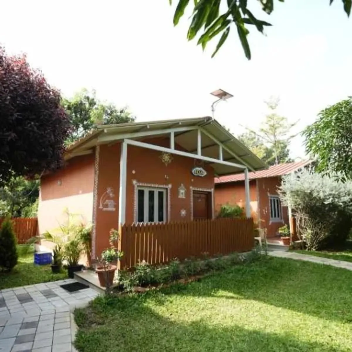 Cob house exterior with wooden facade and garden lawn at Suggee Resort